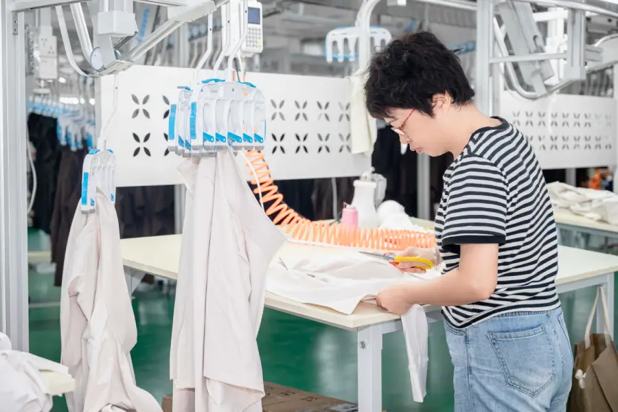 工厂质检员正在使用专业工具仔细检查一件服装