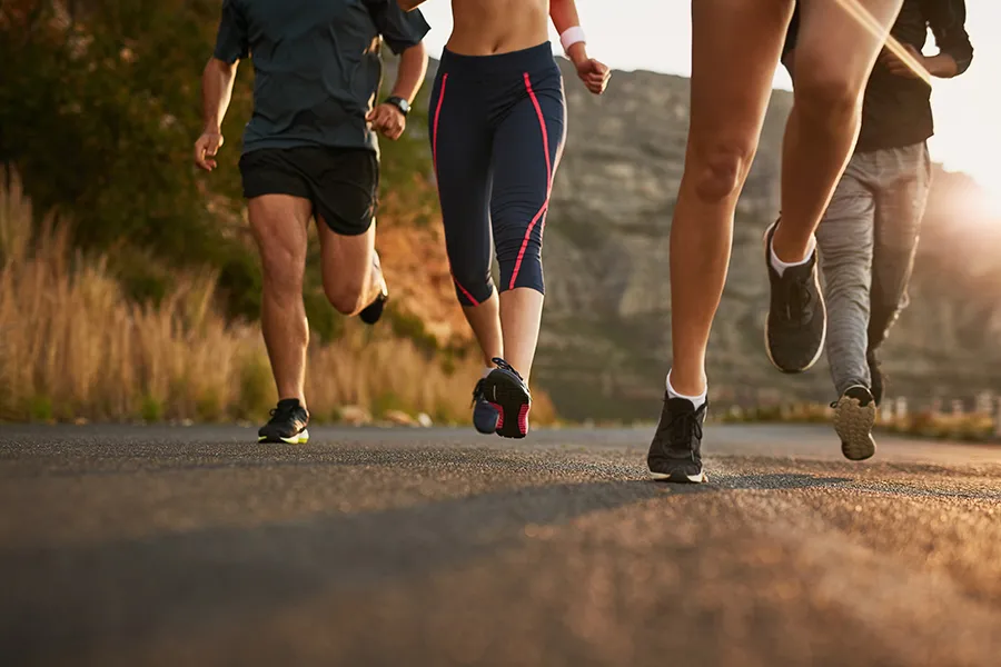 Running road and feet of people wearing Outdoor Apparel in nature for fitness
