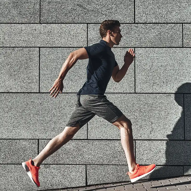 شاب يرتدي ملابس رياضية يركض أثناء ممارسة الرياضة في الخارج