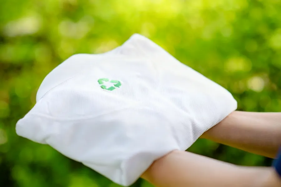 Hand holding a white shirt made from recycled materials